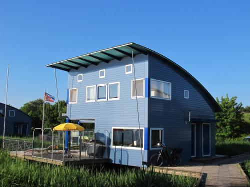 a large blue house with a yellow roof at Ferienhaus SEABIRD by FeWo-PLAN OOST150 mit direktem Zugang ins LAUWERSMEER in Anjum