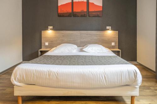 a bedroom with a large bed with two pillows at Hotel Colmar Vignes Eguisheim in Eguisheim