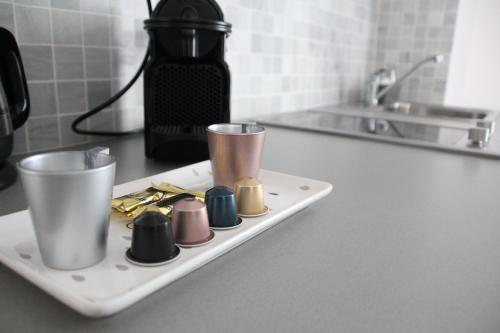 a white tray with different colored cups on a kitchen counter at Cosy Apparts Suresnes La Défense in Suresnes