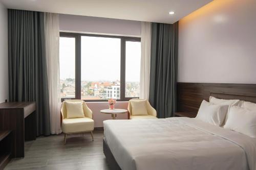 a hotel room with a bed and two chairs at Riverside Quảng Yên Hotel in Quảng Yên