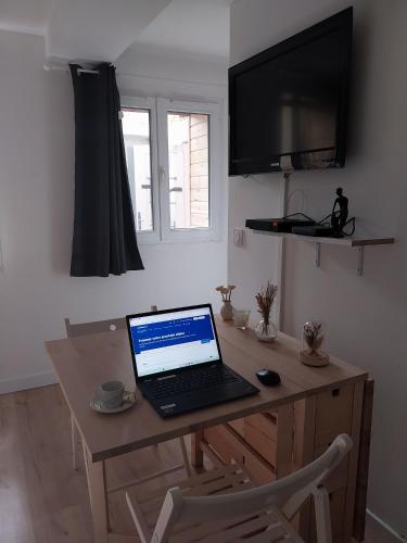 a laptop computer sitting on a wooden desk in a room at Sète Centre ville T2 rénové in Sète