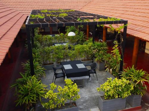 a patio with a black table and chairs and plants at Raj Riveria Hotel in Mūvattupula