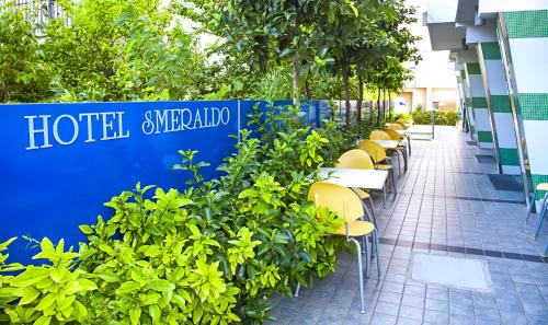 una fila di tavoli e sedie di fronte a un edificio di Hotel Smeraldo a Tortoreto