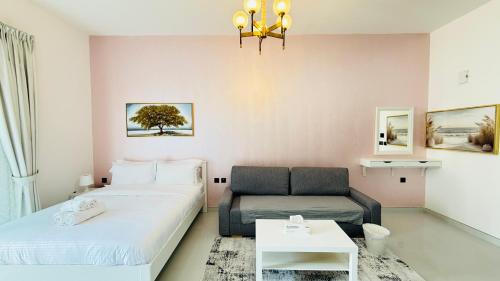a room with two beds and a couch and a table at Lawnz Luxury furnished studio with Balcony Swimming Pool Gym Kids play ground in Dubai