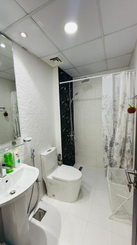 a white bathroom with a toilet and a sink at Lawnz Luxury furnished studio with Balcony Swimming Pool Gym Kids play ground in Dubai