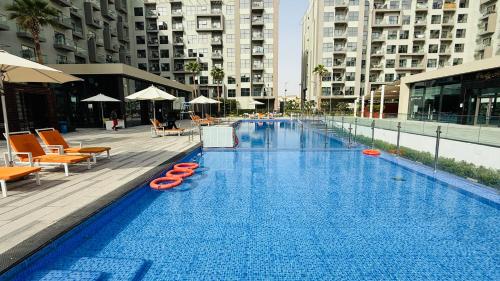 a large swimming pool with orange chairs and buildings at Lawnz Luxury furnished studio with Balcony Swimming Pool Gym Kids play ground in Dubai
