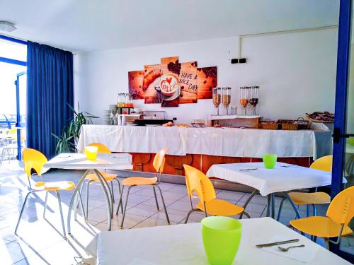 un ristorante con tavoli bianchi e sedie gialle di Hotel Smeraldo a Tortoreto