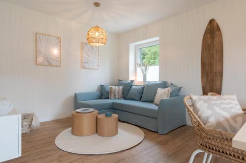 a living room with a blue couch and a table at Küstenbutze im Beach-Style 2 Bedrooms, 2 Bäder , Garten, Terrasse, Top-Modern in Mildstedt