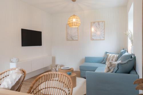 a living room with a blue couch and a tv at Küstenbutze im Beach-Style 2 Bedrooms, 2 Bäder , Garten, Terrasse, Top-Modern in Mildstedt