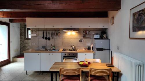 a kitchen with white cabinets and a table with a bowl of fruit on it at Porcaticcio in Casola Valsenio