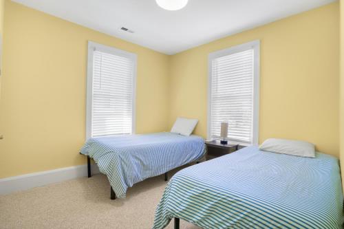 two beds in a room with two windows at Bayside - Classic duplex in historic downtown! in Cape Charles