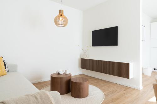 a living room with a couch and a tv on a wall at Küstenbutze im modernen Scandi-Style mit Garten und Terrasse in Mildstedt