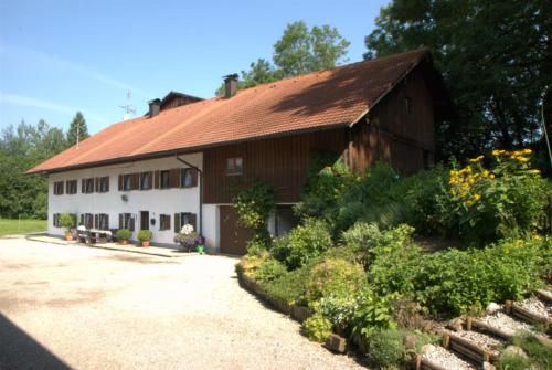 eine Scheune mit rotem Dach und einem Garten in der Unterkunft Ferienhaus, Bauernhof mit Angel- und Badesee, Roßhaupten, Allgäu in Roßhaupten