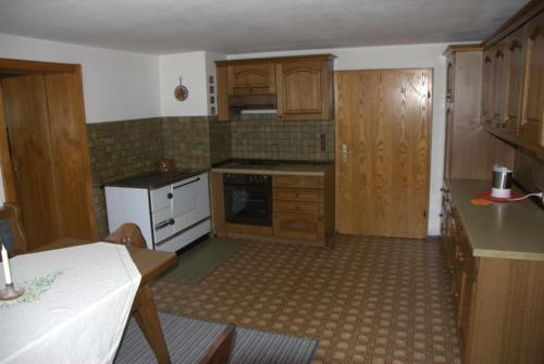 eine Küche mit Holzschränken und weißen Geräten in der Unterkunft Ferienhaus, Bauernhof mit Angel- und Badesee, Roßhaupten, Allgäu in Roßhaupten