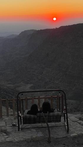 two people laying on a bench watching the sunset at Dana luxury huts in Dana