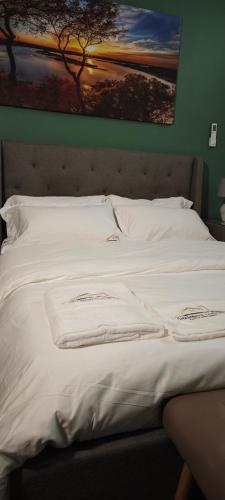 a bed with white sheets and a painting on the wall at Chambres d'Hôtes Centre Ville in Dakar