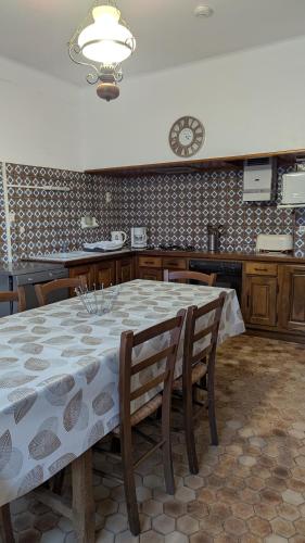 une table à manger avec des chaises et une horloge murale dans l'établissement La maison du sabotier, à Audressein