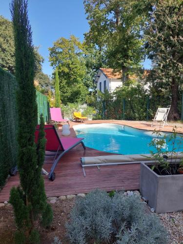 - une piscine avec une terrasse et une chaise à côté dans l'établissement Villa avec piscine parc de Royan, à Royan
