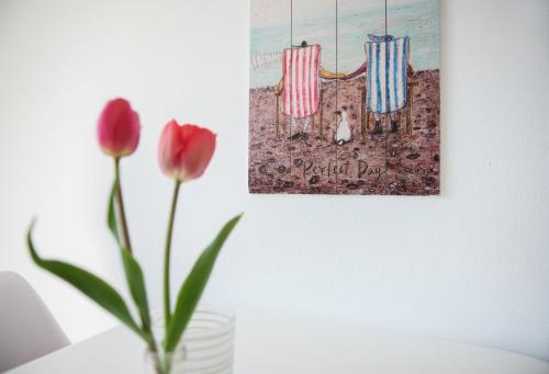 Eine Vase mit zwei roten Tulpen und einem Gemälde in der Unterkunft Bauernhof Höper-Rauert - Reihenhaus 8 in Neujellingsdorf