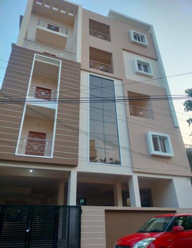 a building with a red car parked in front of it at Marvee Luxus Stay in Coimbatore