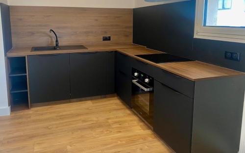 - une cuisine avec des placards noirs, un évier et un comptoir dans l'établissement Appartement plein centre vue mer PROPRIANO, à Propriano