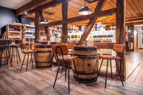 a bar with barrels and stools in a restaurant at Hotel Colmar Vignes Eguisheim in Eguisheim