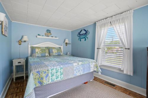 a blue bedroom with a bed and a window at Bue Crab Bungalow - Charming in-town cottage! in Birch Town