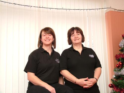 Zwei Frauen in schwarzen Hemden sitzen neben einem Weihnachtsbaum in der Unterkunft Gateway Lodge in Speke