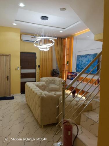 a living room with a couch and a staircase at Rich Garden Homes Shortlet Apartment in Ikota
