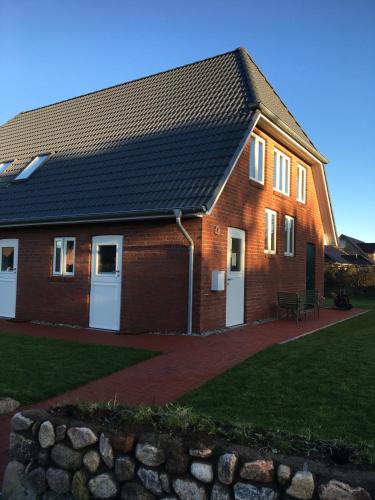 a brick house with white doors and a black roof at Nije Haven Bed & Breakfast in Wrixum