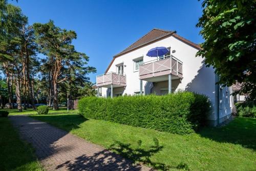 una casa bianca con un cortile verde di Ferienwohnung "Strandgut" a Neuhaus