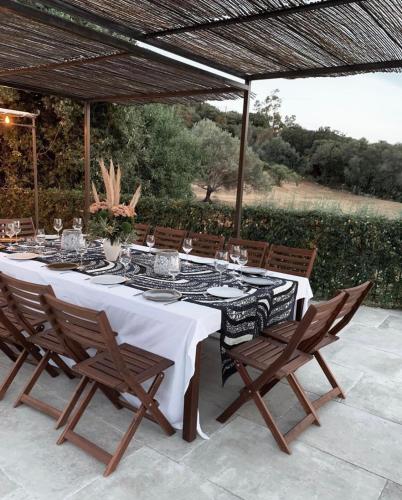 a table with a white table cloth and wooden chairs at Clos des Oliviers in Lumio
