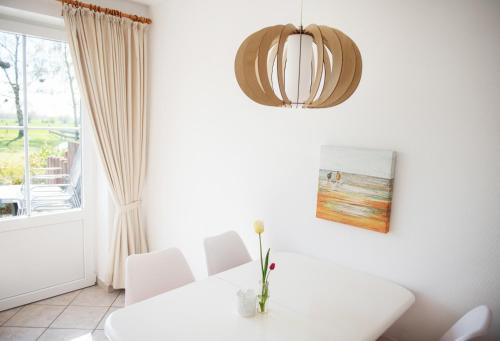 ein weißes Esszimmer mit einem Tisch und einem Fenster in der Unterkunft Bauernhof Höper-Rauert - Reihenhaus 6 in Neujellingsdorf