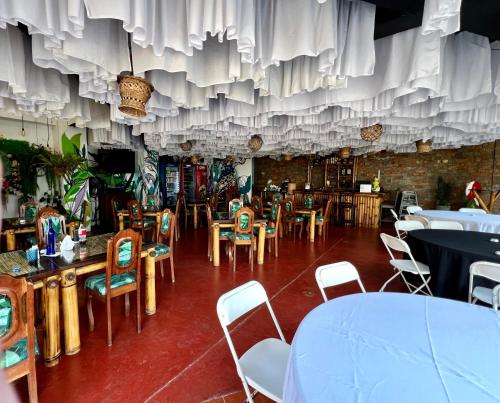 Ceiba BlancaにあるZafra Hotelのテーブルと椅子、カーテン付きの天井が備わるレストラン