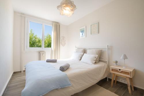 une chambre blanche avec un grand lit et une fenêtre dans l'établissement Chez Ambre et Flo - Queen Size Clim Centre Parking, à Saint-Raphaël