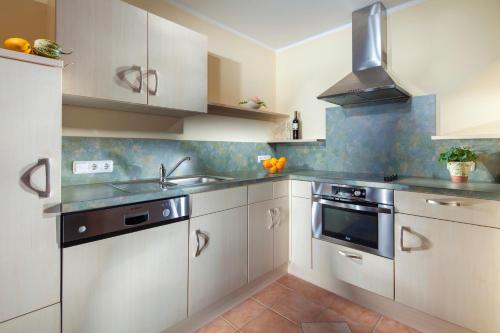 a kitchen with white cabinets and a sink and a stove at Gästehaus Lärcheck Berchtesgaden FeWo Morgensonne in Berchtesgaden