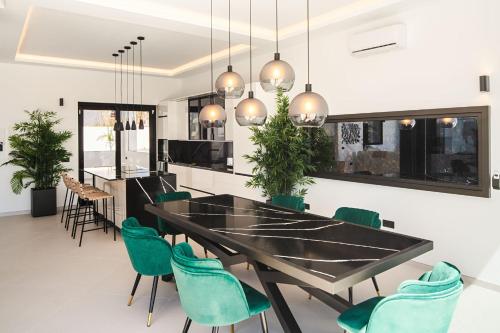 a dining room with a black table and green chairs at TORO by Buenavilla in Puerto Calero