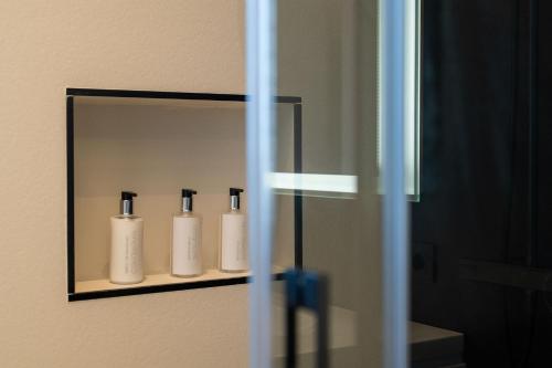 a shelf with four white bottles on a wall at TORO by Buenavilla in Puerto Calero