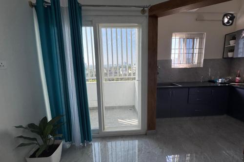 a kitchen with a large sliding glass door with a window at Truelife Whitefield - Premium 1 BHK Apartments - Prime location - Easy access to Main Rd - Metro - ITPL - Fast WiFi - Kitchen - Smart TV - Power backup - Park - Garden views in Bengaluru