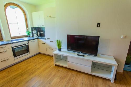 a large kitchen with a tv on a white cabinet at Huberhof 9 by Alpenidyll Apartments in Rohrmoos