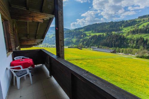 a balcony with a table and chairs and a green field at Huberhof 9 by Alpenidyll Apartments in Rohrmoos
