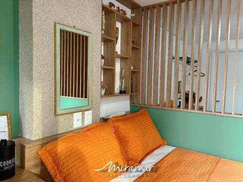 a bedroom with a bed with an orange blanket at Vert House Jardim Oceania - Miramar Hospedagens in Tambaú