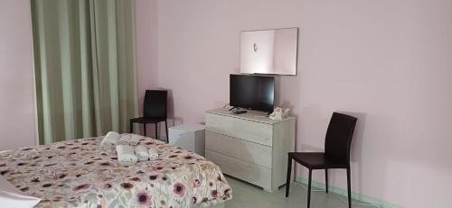 a bedroom with a bed and two chairs and a television at Marico Apartment in Salerno