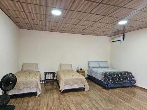 two beds and a couch in a room at Pleasant Hostal Panama in Aserrío