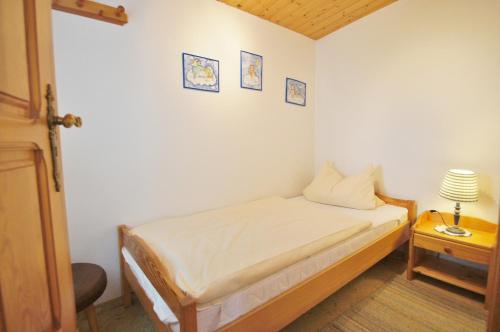 Un pequeño dormitorio con una cama y una lámpara en una mesa. en Ferienbungalow 4, en Dahme