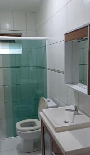 une salle de bain avec toilettes, lavabo et miroir dans l'établissement Casa Fundos na Enseada - 2 Quartos, à São Francisco do Sul