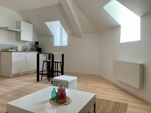 Il comprend un salon blanc avec une table et une cuisine. dans l'établissement DUPLEX Guingamp centre, à Guingamp