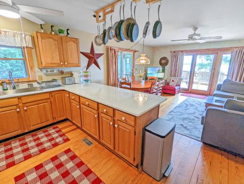 a kitchen with wooden cabinets and a living room at Channel Watch - Waterfront home with private Pier! in Deep Hole