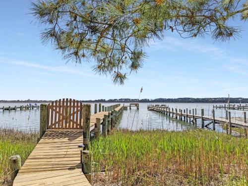 a wooden dock with a bench next to the water at Channel Watch - Waterfront home with private Pier! in Deep Hole