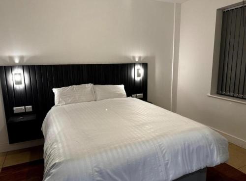 une chambre avec un grand lit blanc avec deux lumières dans l'établissement Luxury Garden Flat London, à Bexleyheath